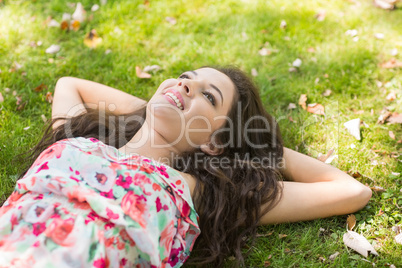 Stylish cheerful brunette lying on the grass