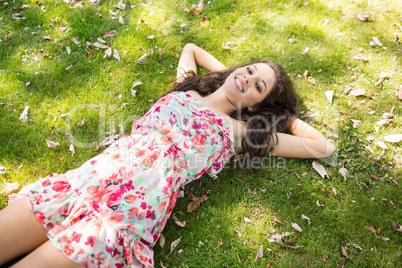 Stylish smiling brunette lying on the grass