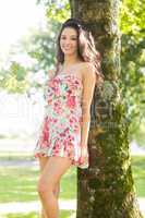 Stylish gorgeous brunette leaning against tree