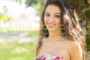 Stylish cheerful brunette leaning against tree