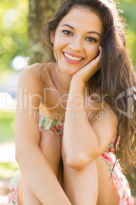 Stylish content brunette sitting under a tree