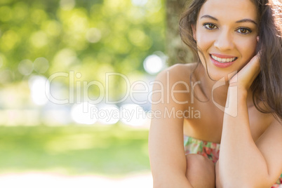 Stylish gorgeous brunette sitting under a tree