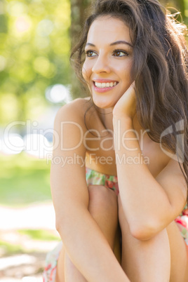 Stylish attractive brunette sitting under a tree