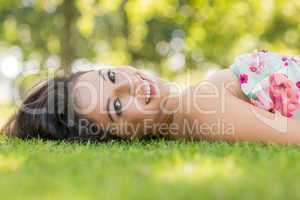 Stylish smiling brunette lying on a lawn