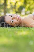 Stylish cheerful brunette lying on a lawn