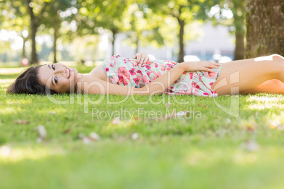 Stylish happy brunette lying on a lawn