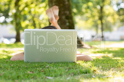 Brunette lying on the grass typing at her laptop