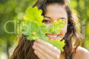 Gorgeous cheerful brunette holding a leaf