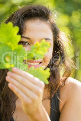 Gorgeous smiling brunette holding a leaf