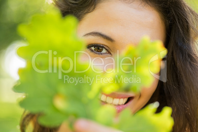 Gorgeous happy brunette holding a leaf