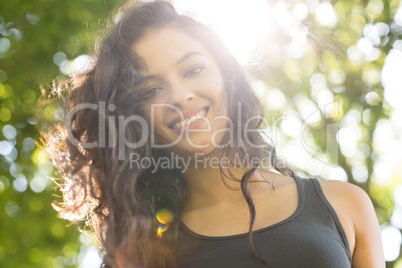 Casual smiling brunette standing on grass in sunlight