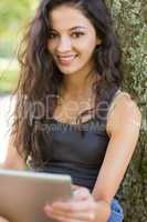 Casual happy brunette sitting using tablet