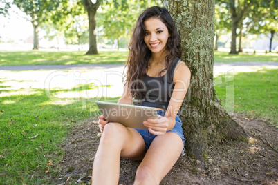 Casual happy brunette sitting holding tablet