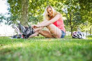 Casual smiling blonde putting on roller blades