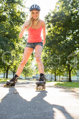 Casual smiling blonde inline skating on pathway