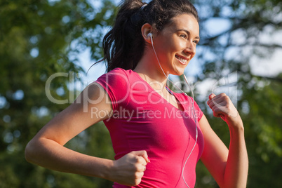 Cheerful young woman jogging in a park