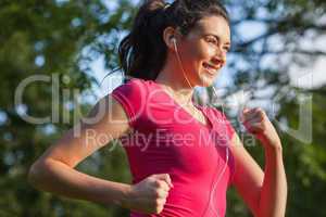 Cheerful young woman jogging in a park