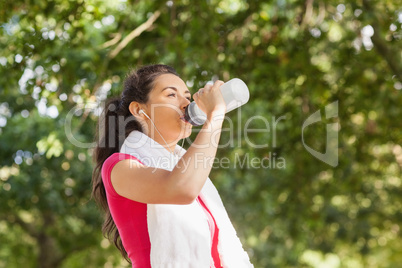 Sporty woman with towel on shoulders drinking water
