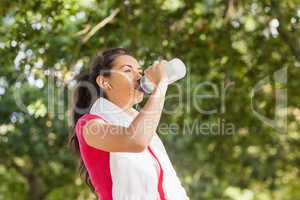 Sporty woman with towel on shoulders drinking water