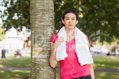 Young sporty woman leaning against a tree