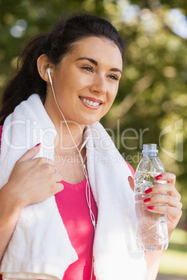 Happy sporty woman wearing sportswear holding a bottle