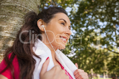 Happy brunette young woman leaning against tree