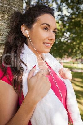 Content brunette woman leaning against a tree