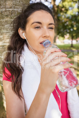 Beautiful sporty woman leaning against a tree