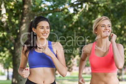 Two sporty women jogging in a park