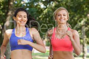 Two beautiful sporty women jogging in a park