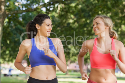 Two friendly pretty women running in a park