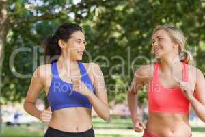 Two friendly pretty women running in a park