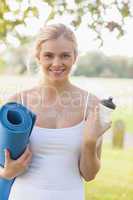 Happy young woman holding an exercise mat