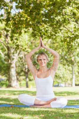 Cute young woman doing yoga sitting on an exercise mat