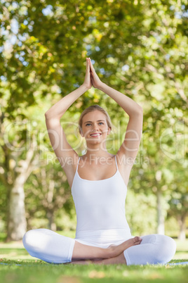 Cheerful smiling woman meditating with hands raised in prayer