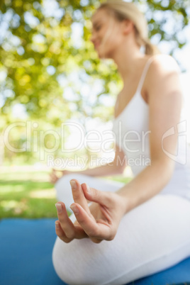 Peaceful young woman sitting on an exercise map meditating