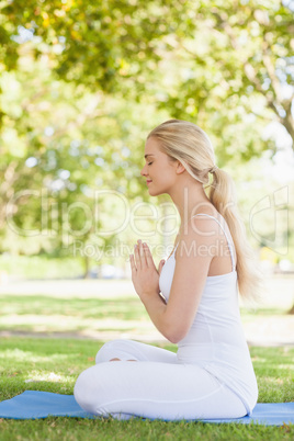 Side view of beautiful calm woman meditating sitting on an exerc
