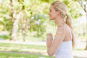 Side view of peaceful young woman meditating sitting in park
