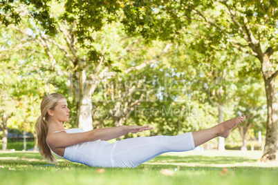 Side view of beautiful woman doing yoga in a park