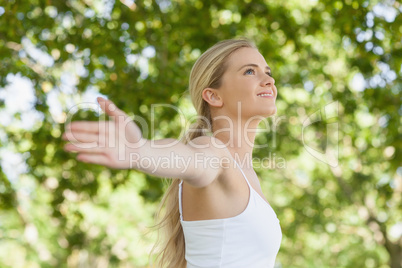 Side view of pretty young woman doing yoga spreading her arms