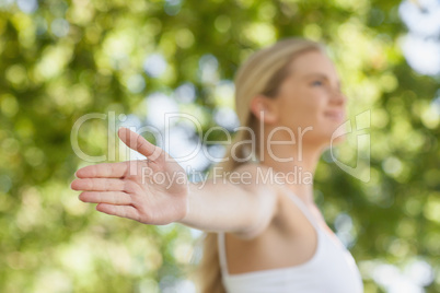 Beautiful ponytailed woman doing yoga spreading her arms