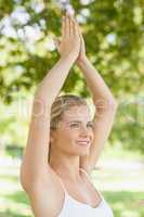 Side view of cheerful young woman doing yoga with hands raised i