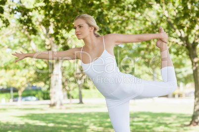 Calm young woman doing yoga standing in a park