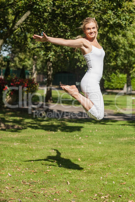 Side view of young cheerful woman jumping spreading her arms