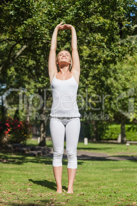 Front view of content young woman stretching her arms in a park