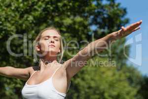 Serious peaceful woman doing yoga in a park