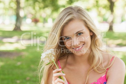 Portrait of lovely young woman showing a white flower