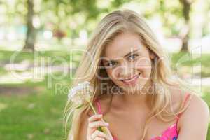 Portrait of lovely young woman showing a white flower