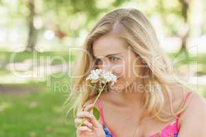 Lovely blonde woman smelling a flower