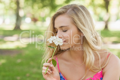 Side view of cute casual woman smelling a white flower